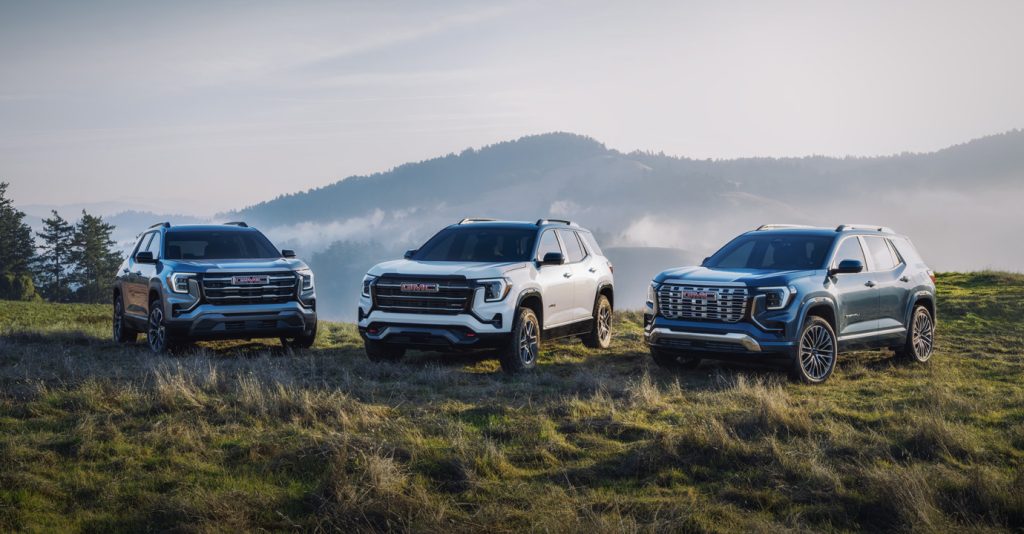 Three 2026 GMC Terrain SUVs in a scenic outdoor setting.
