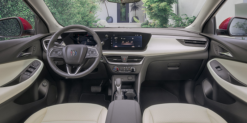 Interior view of a Buick vehicle showing the front cabin, including the steering wheel with Buick logo, digital dashboard display, center touchscreen infotainment system, and climate controls with a clean, modern design.
