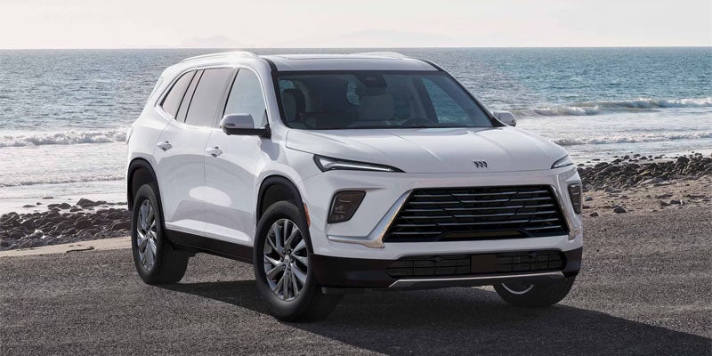 White Buick SUV parked on a coastal road with the ocean in the background.